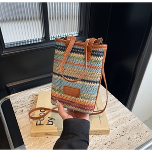 Detail of colorful striped woven bucket bag with leather strap and fashion logo patch