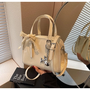 Detail of cream patent leather Boston bag with lace bow and silver balloon dog charm