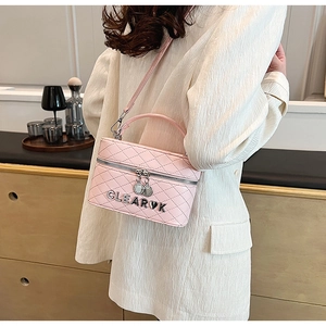Détail du sac bandoulière matelassé rose avec breloque cœur et logo en métal poli