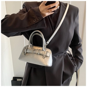 Close-up of metallic silver shell bag with decorative buckles and crossbody strap
