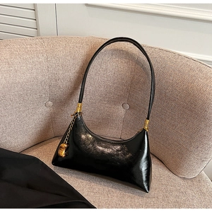 Detail der schwarzen glänzenden Hobo-Tasche mit Goldbeschlägen und Herzanhänger