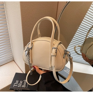 Vue détaillée du sac Boston crème avec texture litchi et chaîne argentée décorative
