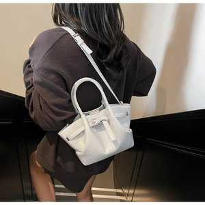 Vue arrière d'un sac seau en cuir gris clair avec poignées et bandoulière sur un mannequin
