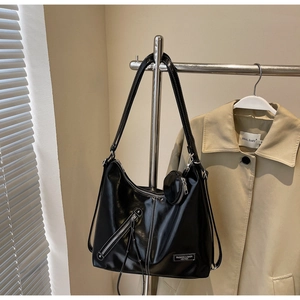 Détail d'un grand sac fourre-tout noir brillant avec surpiqûres blanches et petit porte-monnaie