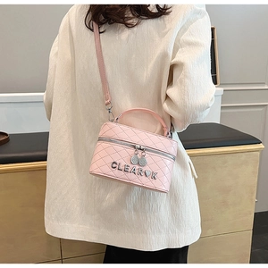 Détail du sac boîte rose matelassé avec logo métallique et bandoulière élégante