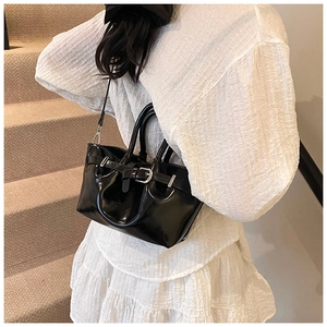 Close-up of glossy black bucket bag with silver hardware and adjustable shoulder strap
