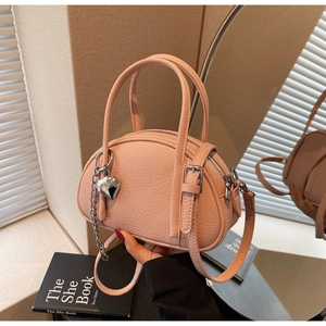 Détail du sac à main rose en cuir grainé avec breloque cœur et doubles poignées