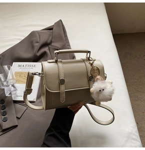 Detail of beige leather handbag with plush sheep charm in a stylish lifestyle setting