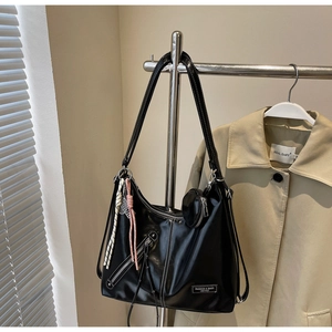 Détail du sac hobo noir verni avec décor zippé et petit porte-monnaie rond attaché