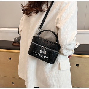 Vue latérale d'un sac bandoulière noir matelassé avec logo cœur et breloques dorées