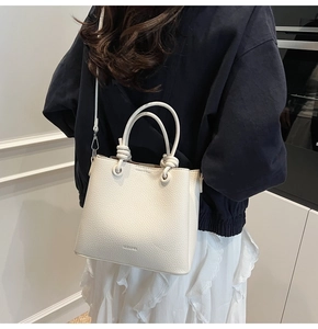 Detail of white lychee leather bucket bag with knotted handle and embossed CLOVER logo