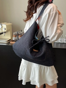 Large denim tote bag with bow detail and printed lining shown on person in cafe