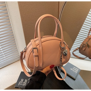 Détail du sac à main rose en cuir grainé avec pendentif cœur et bandoulière réglable