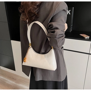 Nahaufnahme der weißen glänzenden Schultertasche mit Goldkette und schmalem Gurt
