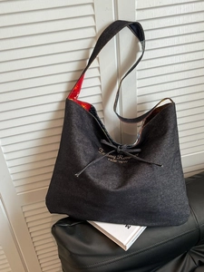 Retro denim tote bag with red floral lining and drawstring closure on leather sofa