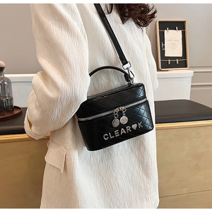 Détail de la boîte sac matelassée noire avec décoration de lettres en métal argent