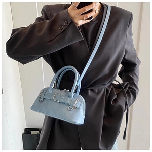 Detail of light blue shell bag with leather strap buckle and silver metal hardware