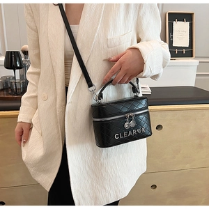 Détail du sac bandoulière en cuir noir matelassé avec logo argenté et double fermeture
