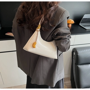 Detailansicht der weißen Halbmond-Umhängetasche mit goldener Kette und Bohnenanhänger