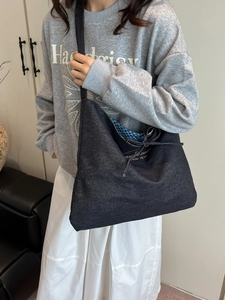 Large capacity denim tote bag with knot closure and blue plaid lining worn by model