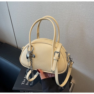 Détail du sac à main en cuir beige avec pendentif coeur argenté et chaîne métallique