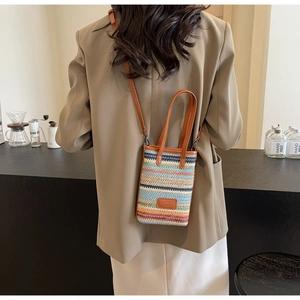 Close-up of a multi-color woven bucket bag with leather strap in a cafe setting