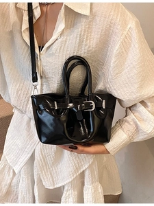 Glossy black patent leather bucket bag with silver hardware shown on a model