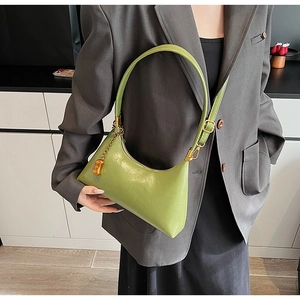 Nahaufnahme einer erbsengrünen Hobo-Tasche mit goldenen Metallteilen und Mode-Anhänger