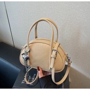 Détail du sac hobo beige avec texture litchi, pendentif cœur et fermeture éclair métal