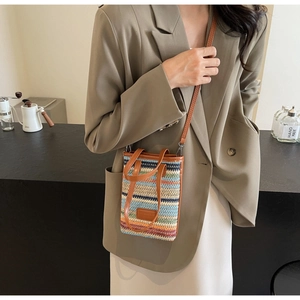 Detailed view of colorful hand-woven straw crossbody bag with brown leather strap