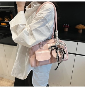 Detalle de bolso de charol rosa con bolsillos delanteros y colgante de lazo de encaje