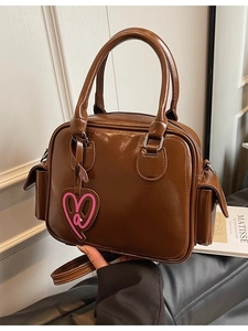 Brown glossy faux leather Boston tote bag with heart pendant and adjustable strap