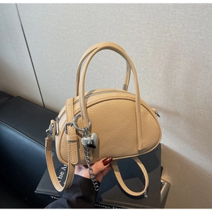 Détail du sac beige en similicuir avec pendentif cœur argenté et texture grainée