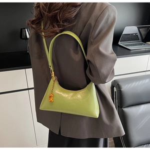 Detail der grünen Leder-Schultertasche mit einem edlen goldenen Bohnen-Anhänger