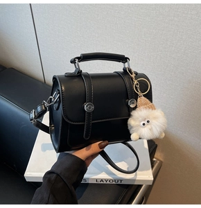 Black vegan leather crossbody bag featuring silver buckles and a plush monster charm detail