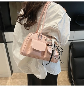 Bolso de hombro rosa de cuero con lazos de encaje mostrado de lado por una modelo