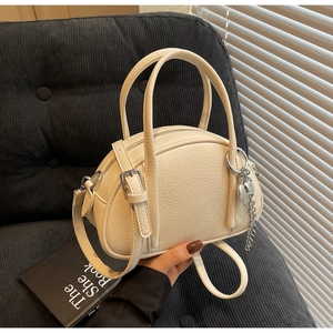 Détail du sac à main en cuir grainé crème avec pendentif cœur et chaîne argentée