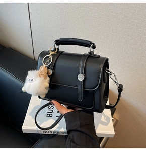Detail of black matte leather mini square bag with silver buckles and plush sheep pendant