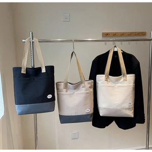 Detail of canvas tote bags with contrast stitching and lucky tag on front pockets