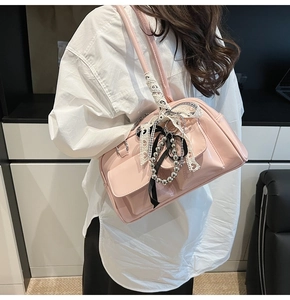 Detalle de bolso rosa de charol con lazos de encaje y adornos plateados de estilo Y2K