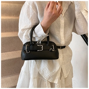 Detail of a black shell bag with silver buckle and smooth faux leather texture