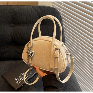 Détail du cuir grainé blanc crème avec breloque cœur argentée sur le sac à main