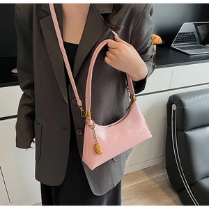 Detail der rosa glänzenden Hobo-Tasche aus Kunstleder mit goldenem Anhänger am Outfit