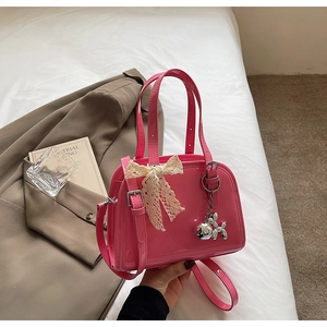 Close-up of rose pink patent leather bag with lace bow and silver puppy charm