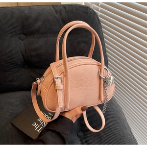 Détail du sac boston en cuir rose avec breloque cœur argentée sur velours côtelé noir