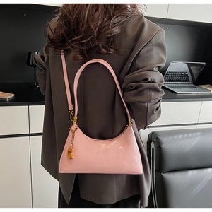 Detail der rosa Lacklederhandtasche mit Goldanhänger und verstellbarem Schultergurt