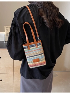 Colorful woven bucket bag with leather straps shown on model in a cozy indoor setting