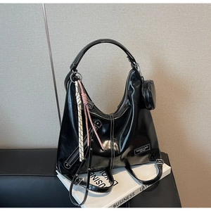 Detail of black glossy leather tote bag with white contrast stitching and mini pouch