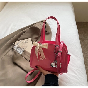 Detail of pink patent leather handbag with lace bow and silver dog charm on brown blazer