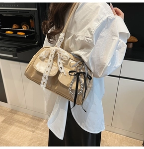 Detalle de bolso de hombro caqui con lazos de encaje y abalorios metálicos